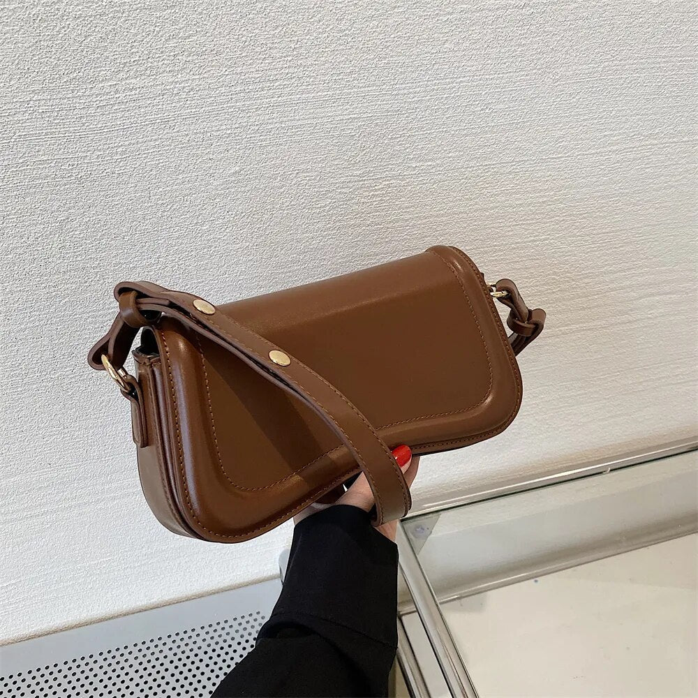 Bolsa Emily estilo baguete com design ondulado. Compacta, elegante e versátil, em material sintético com botão magnético e espaço ideal para o dia a dia.