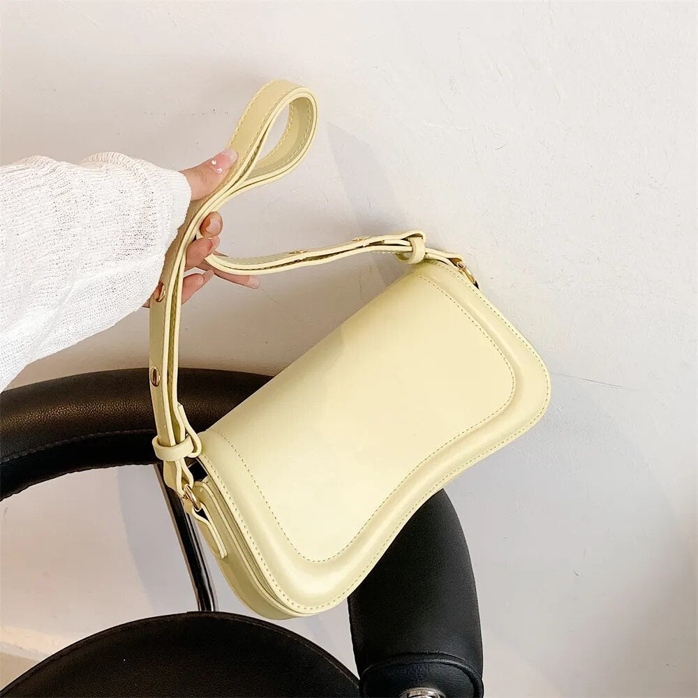 Bolsa Emily estilo baguete com design ondulado. Compacta, elegante e versátil, em material sintético com botão magnético e espaço ideal para o dia a dia.