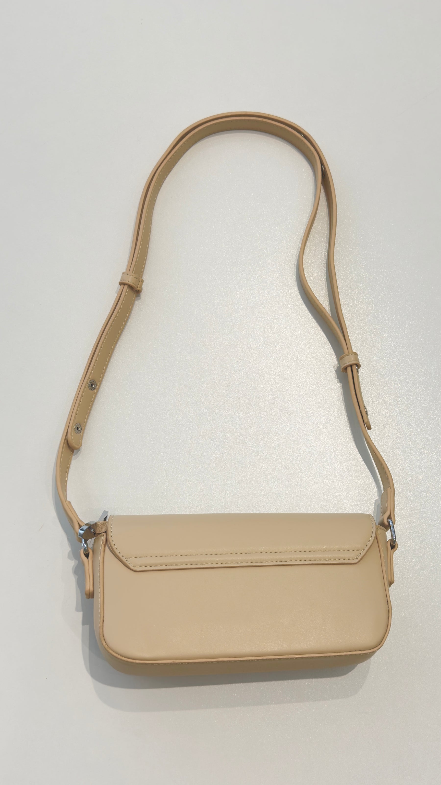 Bolsa Lia em couro legítimo bege, compacta e elegante. Design estruturado, alça regulável e detalhes em prata para usar no ombro ou transversal.