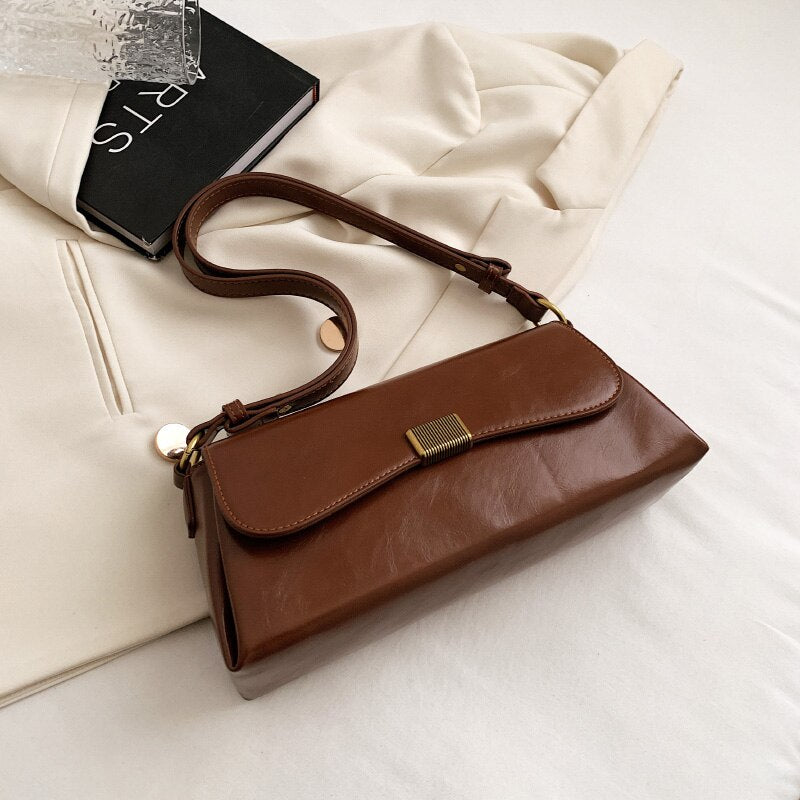 Bolsa Renata em couro legítimo, estilo baguete. Sofisticada e espaçosa, com zíper e botão magnético, perfeita para looks elegantes e versáteis do dia a dia.
