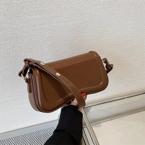 Bolsa Emily estilo baguete com design ondulado. Compacta, elegante e versátil, em material sintético com botão magnético e espaço ideal para o dia a dia.