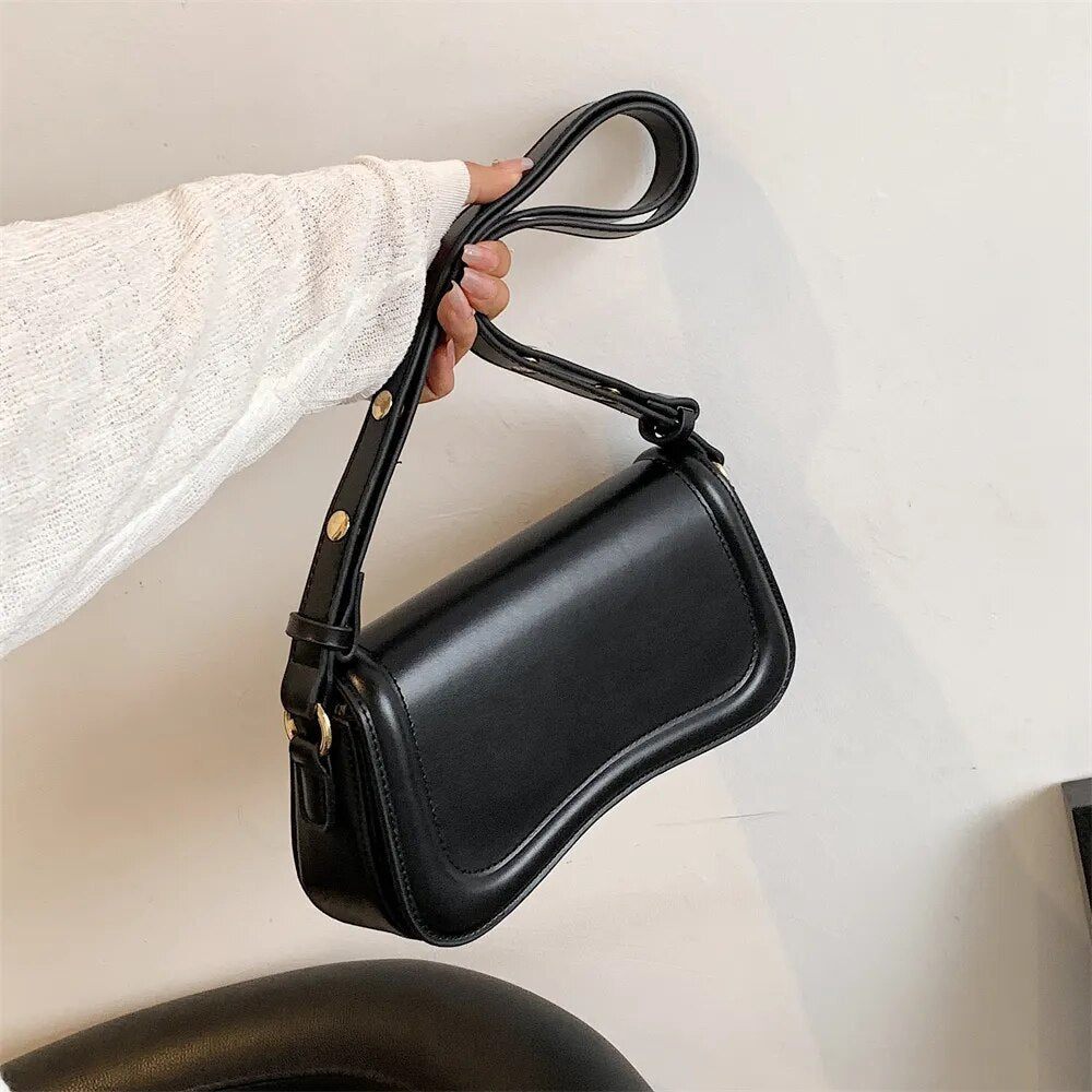 Bolsa Emily estilo baguete com design ondulado. Compacta, elegante e versátil, em material sintético com botão magnético e espaço ideal para o dia a dia.