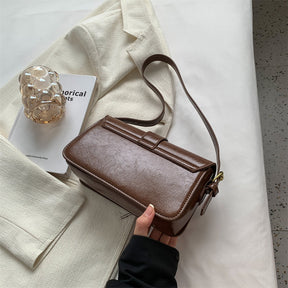 Bolsa Mary estilo baguete, feita em material sintético premium. Compacta, elegante e prática, com zíper, fivela decorativa e espaço para itens essenciais.